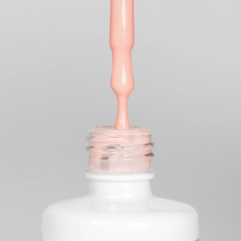 Nahaufnahme einer offenen Longlife UV-Lack Meringue Flasche. Die Farbe ist ein helles Orange-Nude mit hoher Sättigung. Der UV-Nagellack tropft am Pinsel herunter.
