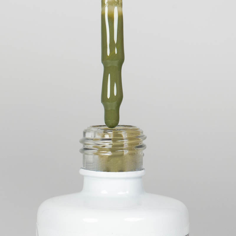 Nahaufnahme einer offenen Longlife UV-Lack Martini Olive Flasche. Die Farbe ist ein gelbliches Grün. Der UV-Nagellack tropft am Pinsel herunter.